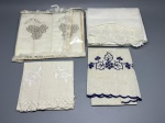 CAMA - MESA - BANHO - Lote de quatro peças finas em tecido claro, ideais para uso litúrgico ou decoração, com bordados artesanais, rendas e detalhes temáticos, incluindo um conjunto na embalagem original, apresentando marcas do tempo e manchas amareladas de guarda.