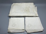 CAMA - MESA - BANHO - Lote composto por toalha de mesa (250x160 cm) em linho claro com ricos bordados florais, detalhes geométricos vazados e barras com acabamento em richelieu e crivo, acompanhada de doze guardanapos coordenados com bordado aplicado em um dos cantos e bainha ajourada. As peças apresentam marcas do tempo e manchas amareladas de guarda.