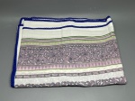 CAMA - MESA - BANHO - Lote composto por toalha de mesa (200x150 cm) em tecido claro com estampa geométrica e floral estilizada em tons de roxo e verde, arrematada com delicada barra em crochê azul nas bordas, acompanhado de três guardanapos coordenados com estampa floral em um dos cantos. As peças apresentam marcas do tempo e manchas amareladas de guarda.
