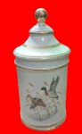 Vaso cônico com tampa em porcelana, apresenta decoração em reserva de patos. Medidas: Alt. 24 x 10 cm.