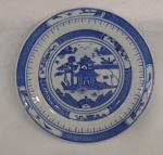 China / BLUE CANTON. Prato Macau ou Pagode em porcelana Jingdezhen de pasta dura. Esmalte azul e branco underglaze. Clássico design de Wu-tong Chinese parasol tree, paisagem de montanha, rio, pontes e pagodes. Medidas:  Diâme. 18 cm. Marca de 7 caracteres chineses no verso. Excelente estado de conservação