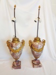 Par de belíssimos vasos montados para abajus em forma de urna, moldados em mármore com veios marcantes e adornados com ornamentos em bronze dourado por toda a peça. Cada um repousa sobre uma base quadrada de mármore. As urnas apresentam duas cabeças de carneiro detalhadas nas laterais, além de motivos botânicos. Medidas: Alt. total 80 x 24 x 20 cm