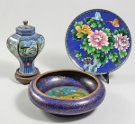 Lote com 3 peças em cloisonné chinês, sendo um bowl decorado com cão de fó amarelo sobre fundo azul no interior e arabescos na parte externa. Período Republicano. Med. 17 x 12,5 x 6 cm, uma urna formato facetado, decorado com paisagens e aves e um pratinho decorado com flores. Med. 16 cm totais e 16 cm de diâmetro.