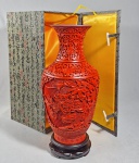 YANGZHOU LACQUER - Excepcional e impecável vaso em laca chinesa vermelho cinnabar esculpida a mão com flores padrões de scrolls de Lotus. Acompanha base em madeira de lei. Novo, em perfeito estado, acomodado em luxuosa caixa original revestida em seda amarela no interior e tecido externo. Acompanha bolsa da embalagem. Med. 30 cm e total 34 cm.