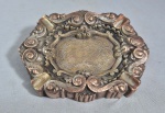 Antigo e pesado cinzeiro em bronze, no estilo D. João VI, cinzelado no estilo Rocaille com volutas e flores. Med. 19.5 x 14.5 cm. Desgastes no banho.