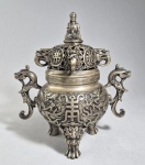 Antigo incensário budista chinês em bronze prateado, com a marca "Dà Qng Yù Zhì". Bojo decorado com ideograma Shou (longevidade), pés trípodes e alças no formato de dragões, borda cinzelada com gregas, tampa decorada com ideogramas que juntos significam: "Luz de Buda", tendo pega no formato de Buda/Bodhisattva sobre flor de lótus. Marca circular no fundo. Possivelmente Republicano. Séc.XX. Alt. 20cm.