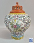 CHINA, DINASTIA QING - Período QIANLONG (1736-1795) - Delicado e pequeno vaso difusor de aromas em porcelana chinesa, decoração Fencai / Família Rosa com técnica 'Boli Bai' sobre fundo branco, com reservas decoradas com pintura de pássaros, lótus, crisântemos, peônias e borboletas, ladeadas por folhagens de lótus e bordas de ruyi. Molde manual, pasta branca translucida de densidades diferentes, vistas através da luz. Base (footrim) com pasta branca visivel e huoshihong. Marca azul em zhuanshu manuscrita no fundo. Tampa fenestrada e monocromática em esmalte vermelho de ferro (iron-red), segundo tradição estética da corte Qing (imitação de materiais): onde o contraste entre corpo policromado e tampa monocromática é intencional. Esse tipo de tampa em porcelana com esmatação vermelha emulava o aspecto visual de laca vermelha cinzelada (Tihong ) ou de cerâmica tradicional de argila púrpura. 19 cm.