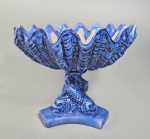Centro de mesa em ceramica italiana azul hortência no formato de grande concha sustentada com haste no formato de golfinhos estilizados. Sem marca. Med. 23 x 30 cm.