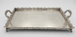 BRASIL, SÉC. XIX/XX - Grande bandeja tabuleiro em metal branco, pode ser usada como bandeja bar. Borda e alças cinzeladas com parreiras e uvas, borda recortada e vazada, apoiada sobre 4 pés de garra, med. 71 x 42 cm (de alça a alça).