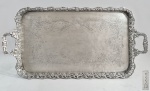 BRASIL, SÉC.XIX - Grande bandeja tabuleiro em prata brasileira, marca de pseudo contraste P COROADO com LAUREL, utilizado pelo prateiro Francisco Duarte da Graça (Atrib), punção conhecida como marca BR-23 no inventário de 'Marcas de Contrastes e Ourives Portugueses e brasileiros" de Fernando Moitinho, e ainda marcada com "CARRETILHA" e Letra O. Fundo com exuberante cinzelado de flores e folhagens, galeria, alças e pés cinzelados com folhas de Parreira e uvas. Med. 61 x 33 cm com alças. Peso: 2.530 gramas. OBS: A mesma marca, foi utilizada em algumas peças por outro prateiro do século XIX, cujo nome não é identificado conhecido como BR-94,98-A e BR 120.