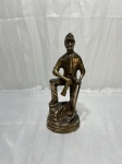 Estatueta decorativa em latão maciço representando a figura de um minerador uniformizado com picareta sobre base rochosa, de fabricação indiana. Medindo 22cm de altura.