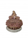 Rebis | Boneca em porcelana da marca Rebis, com vestido rendado em camadas e aplicações florais., pequenas perdas na reda, e faltando um adono na mão esquerda , marcas do tempo  ,  -dim- 18x12x16cm.