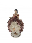 Rebis | Boneca-bailarina produzida em porcelana , sentada, com saia rendada em camadas nas cores vinho e branco, penteado com coque e aplicação floral na base, sem um dos pés, pequenas perdas na renda , marcas do tempo    -dim- 10x10x16cm.