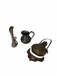 Lote com 3 objetos decorativos em metal: vasinho em formato de cisne com corpo canelado, pequena jarra/leiteira com alça, e frasco de perfume/incensário de estilo oriental com corrente para suspensão, aplicação de pedra vermelha facetada e placa ornamentada com motivos florais em relevo. Marcas do tempo.