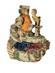 Fonte decorativa produzida em gesso com rica pintura policromada, representando cena campestre com figuras de crianças, árvores e lago com flores, precisa revisar elétrica. -dim- 25x25x30cm.