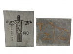 Lote composto por 2 placas decorativas produzidas em pedra-sabão com os temas `Corcovado Rio` e `Pão de Açúcar Rio` — peças charmosas que exaltam os cartões-postais cariocas. Marcas do tempo. -dim- 19x25cm.
