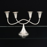 METAL PRATEADO, um (1) candelabro para quatro lumes, base cônica, bobeches assentadas sobre tubos cilíndricos, vergados e soldados, marca WOLFF (tradição desde 1894), medindo 30 cm comprimento e 17,5 cm altura, vide foto.