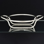 METAL PRATEADO, um (1) suporte para travessa circular, confeccionado em tubo cilíndrico, vergado e soldado, sem marca de manufatura aparente, medida interna 22 cm diâmetro, vide foto.