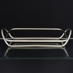 METAL PRATEADO, um (1) suporte para travessa retangular, confeccionado em tubo cilíndrico, vergado e soldado, sem marca de manufatura aparente, medida interna 36,5 x 23,5 cm, vide foto.