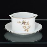 PORCELANA, uma (1) molheira com presentoir acoplado, bicado na borda, ornada com rosas, tom sir tom, detalhes prateados, modelo MEDAILLON, manufatura RENNER (Porto Alegre, RS, fundada em 1942; em 1998 foi vendida para a Vista Alegre de Portugal; em 1999 mudou a razão social para Vista Alegre do Brasil), medindo 17 cm diâmetro, vide foto.