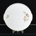 PORCELANA, um (1) medalhão para torta ou bolo, ornado com rosas, tom sir tom, detalhes prateados, modelo MEDAILLON, manufatura RENNER (Porto Alegre, RS, fundada em 1942; em 1998 foi vendida para a Vista Alegre de Portugal; em 1999 mudou a razão social para Vista Alegre do Brasil), medindo 27 cm diâmetro mais o prolongamento das abas, vide foto.