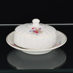 PORCELANA, uma (1) antiga manteigueira com tampa e presentoir acoplado, modelado em caneluras verticais, ornamentação floral policromada, arremates com frisos a ouro, sem marca de manufatura aparente, medindo 15,5 cm diâmetro, vide foto.