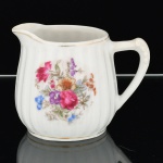 PORCELANA, uma (1) antigo cremeira, modelado em caneluras verticais, ornamentação floral policromada, arremates com frisos a ouro, sem marca de manufatura aparente, desgastes na douração, medindo 9 cm altura, vide foto.