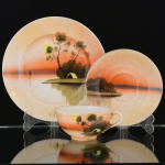 PORCELANA JAPONESA, um (1) trio para chá (xícara, pires e prato de bolo), ornamentação pintada a mão em policromia, representando paisagem lacustre com casebre, marca representada pela letra H dentro de losango e os caracteres: acima Ni  Pon (Japão), abaixo produzido em Kutani, arremates a ouro com sinais de desgastes, medindo a maior peça 18,5 cm diâmetro, ideal para coleção de cristaleira, vide foto.