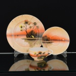 PORCELANA JAPONESA, um (1) trio para chá (xícara, pires e prato de bolo), ornamentação pintada a mão em policromia, representando paisagem lacustre com casebre, marca representada pela letra H dentro de losango e os caracteres: acima Ni  Pon (Japão), abaixo produzido em Kutani, arremates a ouro com sinais de desgastes, medindo a maior peça 18,5 cm diâmetro, prato quebrado e colado, ideal para coleção de cristaleira, vide foto.