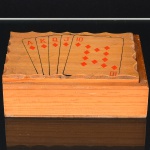 DIVERSOS, uma (1) caixa para acondicionar dois baralhos, acompanha bloco de anotações, faltam os baralhos, confeccionada em madeira, tampa ornada com Royal Street Flush, medindo 14,5 x 11,5 x 4,5 cm, pequeno quebrado próximo da dobradiça, vide foto.