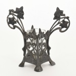 WMF, um (1) vaso floreiro com estrutura vazada em elementos vegetalistas, possui perdas, mossas e pequenos defeitos, marca Württembergische Metallwaren Fabrik (fundada em 1853 em Geislingen, como Metall-Waren-Fabrik Straub & Schweizer, em 1862 foi medalha de ouro na Exposição Mundial em Londres, a partir de 1880 mudou a razão social para o nome atual), marcas auxiliares: I/O (garantia de uma grama de prata depositada por decímetro quadrado); B (confeccionado em pewter ou antimônio), recipiente em vidro da marca R. KANITZ  RIO (antiga fabrica de perfumaria fundada em 1884 por imigrantes húngaros, segunda mais antiga industria de cosméticos e perfumaria do Brasil, depois da Granado, localizada na Rua Washington Luís 117, Centro, RJ, também tem entrada pela Rua do Riachuelo, desativada na década de 80, porém a perfumaria ainda existe no Engenho Novo, RJ), incolor e translúcido com trincas e bicados, altura total 18,5 cm, vide foto.