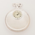 RELÓGIO, um (1) de algibeira (bolso), CÓPIA de relógio antigo, mostrador branco com algarismos romanos, caixa em metal prateado, medindo 52 mm diâmetro, com duas tampas ambas em relevo radiado e com visores para ver o mostrador e funcionamento do mecanismo, mecânico, a corda, parado, vide foto.