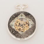RELÓGIO, um (1) de algibeira (bolso), CÓPIA de relógio antigo, mostrador com algarismos romanos e visor, caixa em metal prateado com detalhes grafitados, tampa dupla a da frente vazada, medindo 46 mm diâmetro, mecanismo a corda funcionando e sem garantia, vide foto.