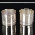 METAL PRATEADO, par (2) porta guardanapos cilíndricos, ornados com listras, sem marca de manufatura aparente, medindo aproximadamente 4 cm diâmetro e 3 cm altura, vide foto.