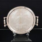 METAL PRATEADO, uma (1) bandeja circular, fundo em baixo relevo com pérgulas, volutas e elementos vegetalistas, alças em fumo de rolo, marca BELPRATA, medindo 36,5 cm diâmetro, vide foto.
