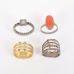 BIJUTERIA, quatro (4) anéis distintos, confeccionados em metal dourado e prateado, um com cabochão de coral ou símile na tonalidade, um com  cravação em pedra ou vidro facetado, incolores e translúcidas, tamanhos variados do 19 ao 26, vide foto.