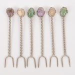 TALHERES, seis (6) garfinhos para petisco, confeccionados em metal prateado, cabo em torçaide, extremidades com pedras variadas: quartzo, ametista, ágata, etc., medindo 9 cm comprimento, vide foto.