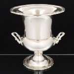 METAL PRATEADO, uma (1) champanheira de pé alto no formato de cachepô, padrão dito Médici, ornamentação relevada em frisos e conchas, marca EBERLE (Abramo Eberle 1880, Monte Magrè 1945, Caxias do Sul, veio com uma das primeiras levas de imigrantes italianos para o Brasil em 1884 junto com seus pais Giuzeppe Eberle e Luigia Zanrosso, seu pai abriu uma pequena funilaria mas como tinha que trabalhar na lavoura quem cuidava era a mãe e o pequeno Abramo ajudava na funilaria; em 1896 quando o pai resolveu vender a funilaria para concentrar os esforços da família na lavoura Abramo, com 16 anos de idade, se propôs a comprá-la do pai, em 1918 já com o nome Abramo Eberle & Cia iniciou a fabricação de talheres e utensílios de mesa, morreu em 1945 com 65 anos de idade e os filhos deram continuidade aos negócios até 1984 quando venderam para o Grupo Zivi), medindo 265,5 cm altura, vide foto.