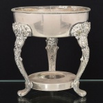METAL PRATEADO, um (1) antigo suporte para recipiente circular, base trípode relevada em flores e volutas com terminação em garra, amarração em plato com concavidade para queimador, borda com rachados, puncionado MFG Corp MRR Made in USA, anos 50/70, medindo 16 cm altura e 14 cm diâmetro, vide foto.