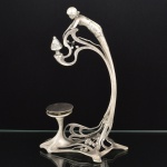 METAL PRATEADO, uma (1) antiga base para fruteira, período Art Nouveau, cerca de 1900, base curvilínea vazada em elementos vegetalistas, haste terminando em figura feminina, possui, perdas, mossas e sinais de restauro, medindo 33 cm altura, vide foto.