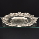 METAL PRATEADO, uma (1) fruteira baixa, fundo com ornamentação em baixo relevo e borda cinzelada, padrão D. JOÃO V, relevada em conchas, volutas e elementos vegetalistas, sem marca de manufatura aparente, medindo aproximadamente 37 cm diâmetro, vide foto.