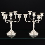 METAL PRATEADO, par (2) candelabros para cinco lumes cada, base cônica e em degraus, fuste no formato de balaustre de onde saem hastes de sustentação das bobeches, sem marca de manufatura aparente, medindo 23 cm altura, vide foto.