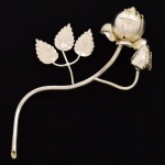 ESCULTURA, uma (1) representando rosa, confeccionada em metal prateado, medindo 18 cm comprimento, vide foto.