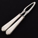 METAL PRATEADO, um (1) quebra nozes, marca WOLFF (tradição desde 1894), cabo com ornamentação relevada em frisos e volutas, medindo 17 cm comprimento, vide foto.