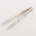 METAL PRATEADO, um (1) quebra nozes, com cabo em torçaide, terminações em cones canelados, marca francesa CHRISTOFLE, medindo 15,5 cm comprimento, vide foto.