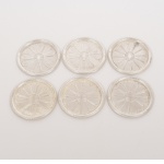 METAL PRATEADO, seis (6) porta copos com borda relevada em frisos intercalados por X, padrão Império Napoleônico, fundo em relevo com flor estilizada, medindo 8,5 cm diâmetro, vide foto.