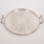 METAL PRATEADO, uma (1) bandeja circular, fundo em baixo relevo com pérgulas, volutas e elementos vegetalistas, alças em fumo de rolo, medindo 43,5 cm diâmetro mais as alças, marca BELPRATA, vide foto.