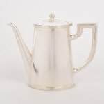 METAL PRATEADO, um (1) bule para café, ornamentação relevada no padrão Império Napoleônico com frisos intercalados por X, pega da tampa na forma de carrapeta, bojo ligeiramente cônico, marca FRACALANZA (tradição desde 1884), medindo 18 cm altura, vide foto.