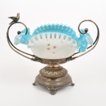 VIDRO E METAL PRATEADO, uma (1) antiga fruteira veneziana, tonalidades azul e branca, opalinada, ornamentação com esmaltação pintada a mão representando flores e borboletas, borda drapeada com quebrados e perdas, alça com terminação macetada faltando um pássaro em um dos lados,  base circular relevada em perolados e elementos vegetalistas, medindo aproximadamente 32,5 x 21 x 27,5 cm, vide foto.