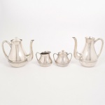 METAL PRATEADO, baixela para chá e café com quatro (4) itens: 2 bules com tampa; 1 açucareiro sem a tampa e 1 cremeira com rachados na borda, ornamentação com frisos horizontais, alças curvilíneas, pegas das tampas em carrapetas, marca WOLFF (tradição desde 1894), medindo a maior peça 17,5 cm altura, vide foto.